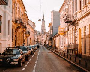 cars parked on side of the road in between buildings during daytime