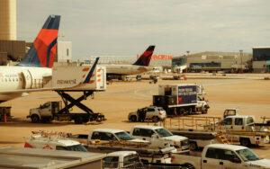 Two airplanes parked at an airport with ground service vehicles nearby.
