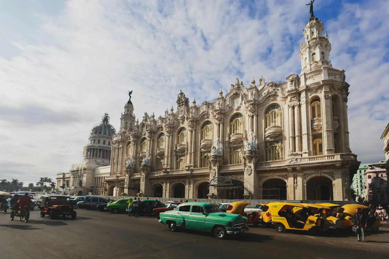Vintage cars line the streets in front of a historic Cuban building in Havana, capturing the city's charm.