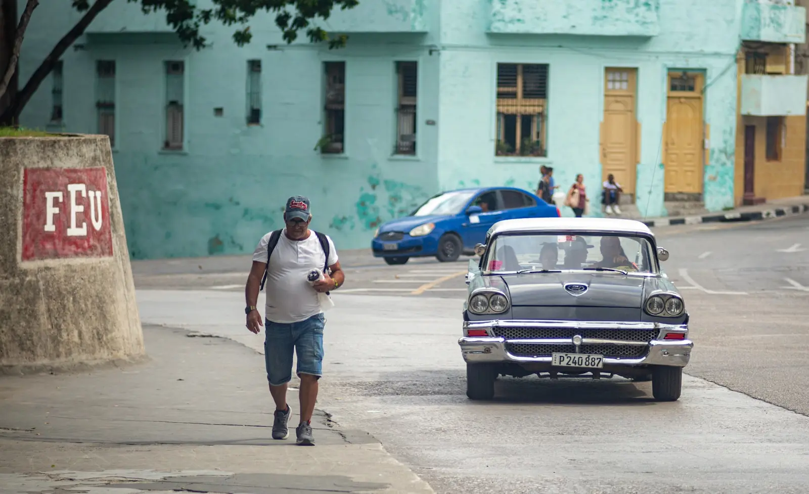 Photo by Ricardo IV Tamayo Man walks past vintage car on street