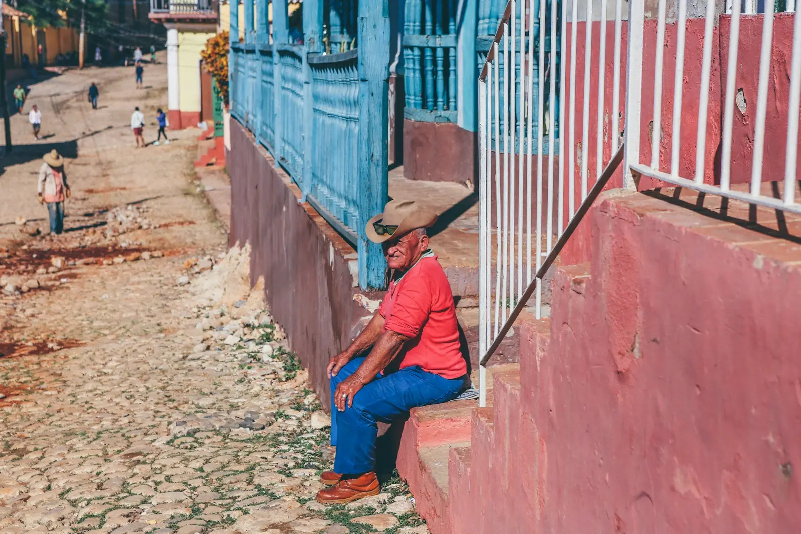 Photo by Nick Karvounis man sitting on red concrete stair in front of house during daytime