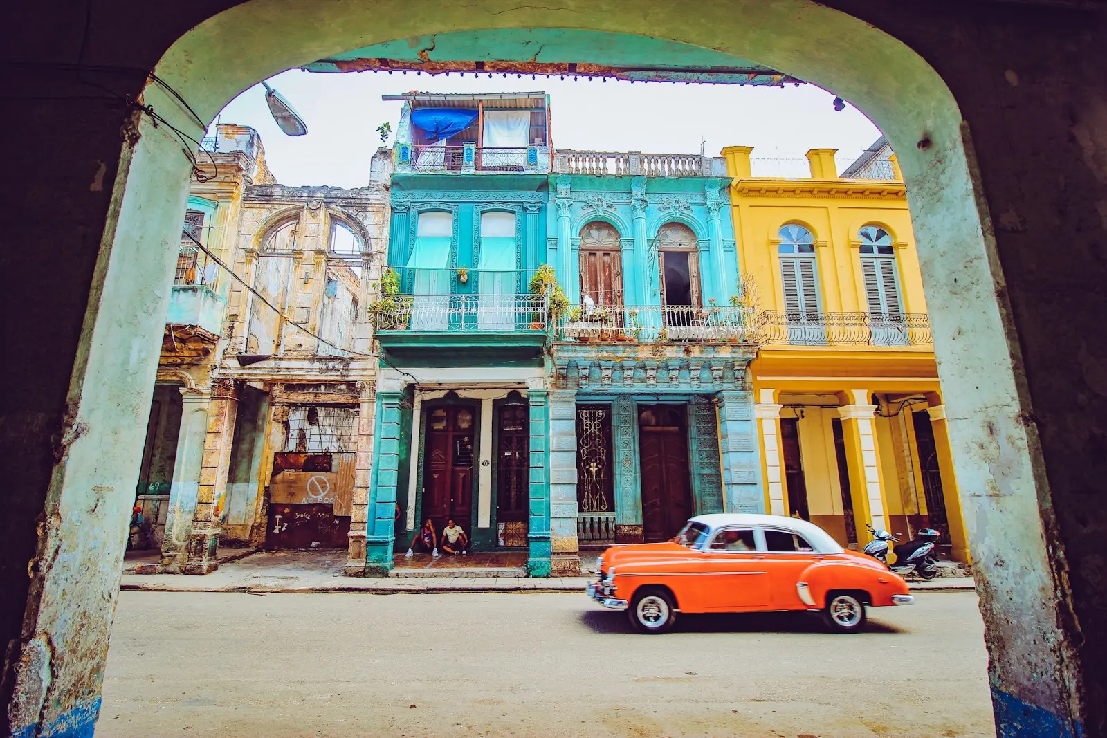 orange and white sedan parked beside brown concrete building during daytime