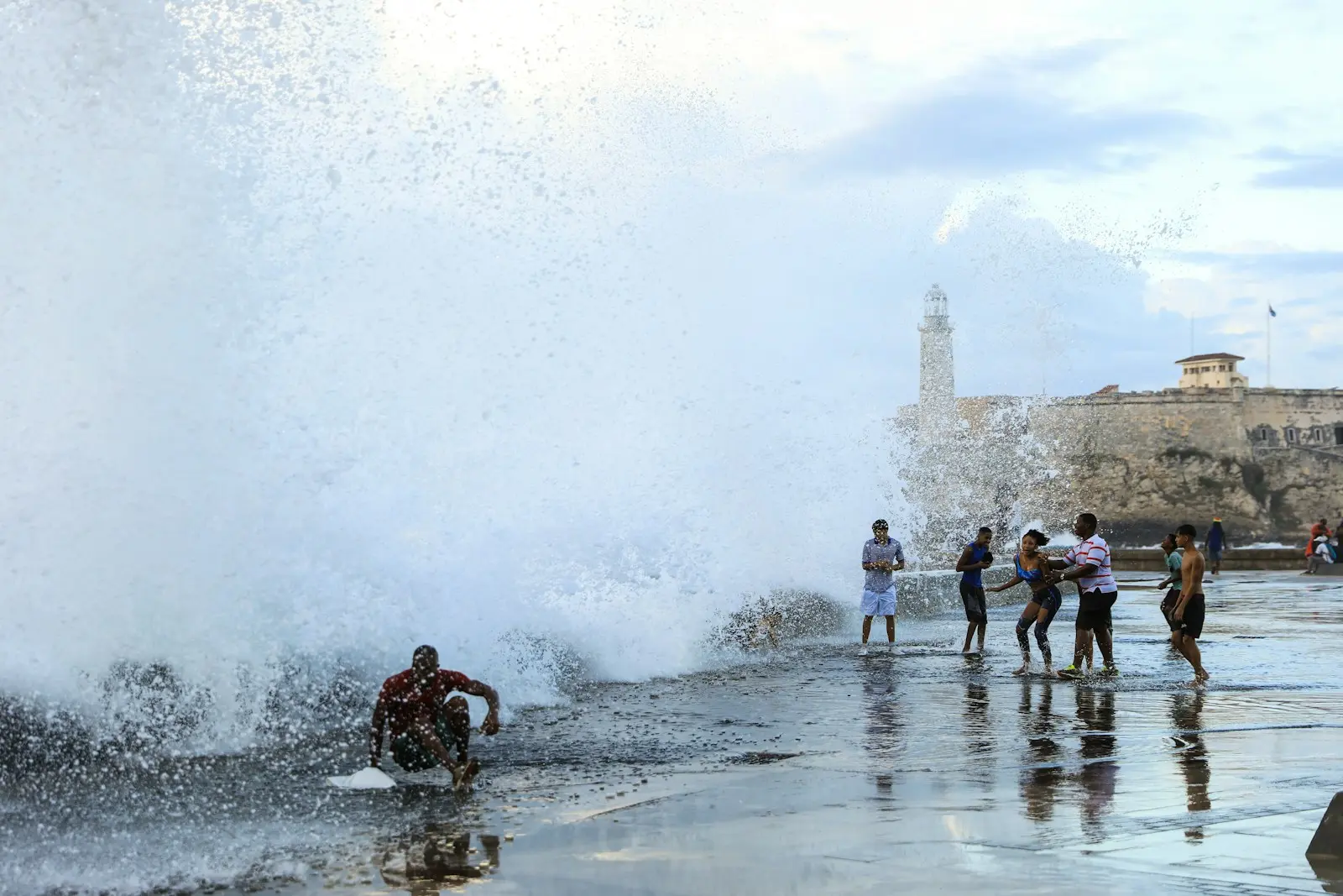 a group of people standing on top of a beach next to a wave