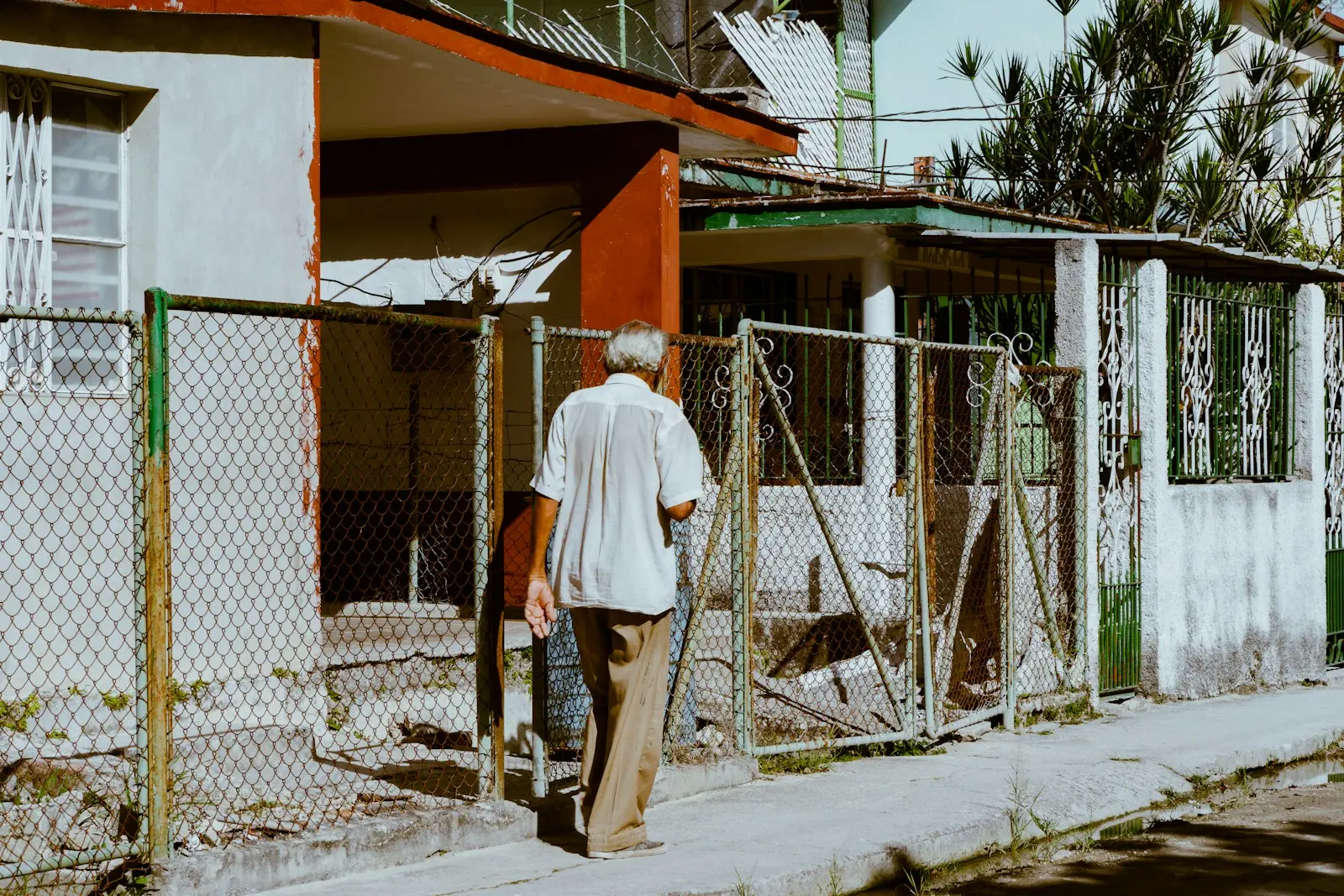 a man walking down a street next to a fence