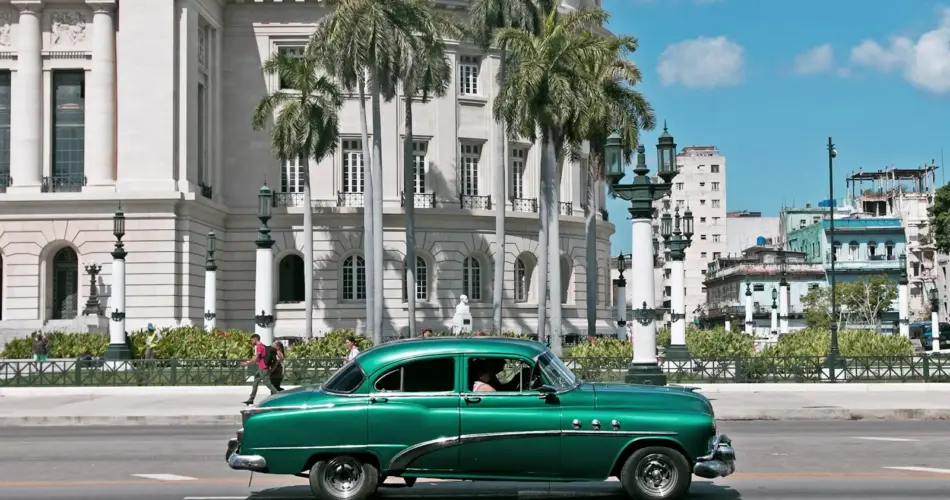 green sedan parks near white building